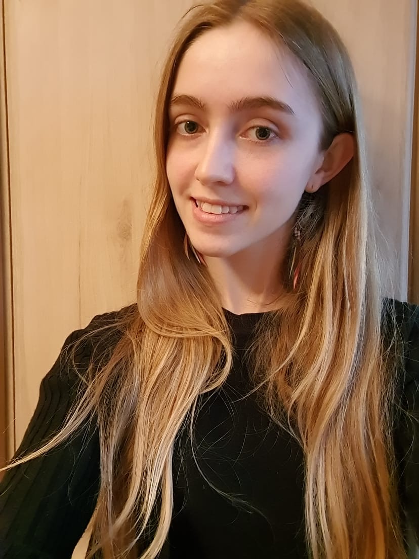 a photo of Louise - a white woman with long blond hair and a black top, smiling and looking at the camera