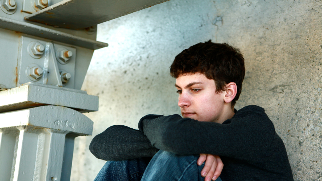 image of a young person leaning up against a wall looking deep in thought