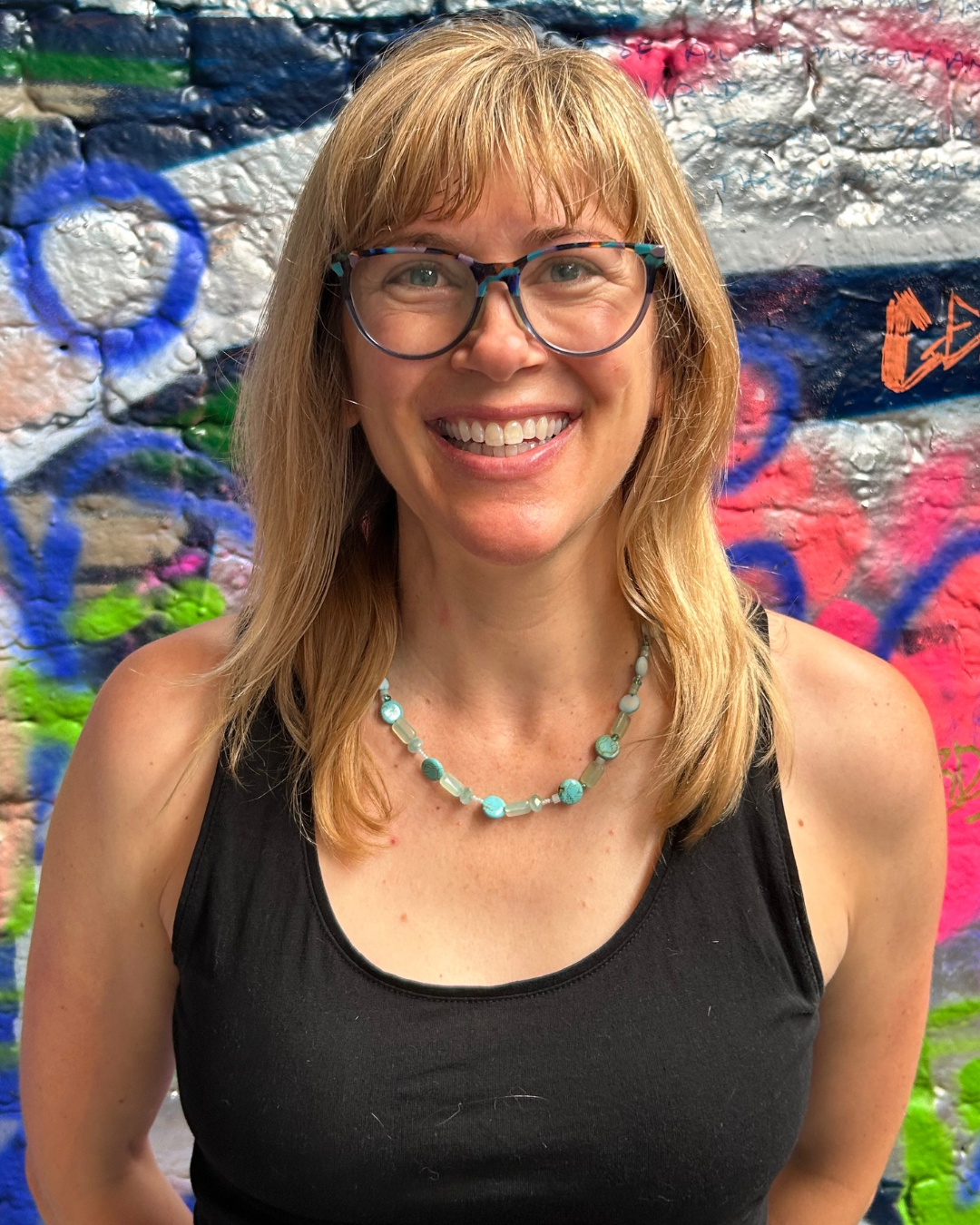 photo of Laura - a white woman with blond hair and glasses wearing a black vest